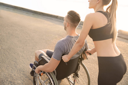 运动妇女帮助年轻人在轮椅室外