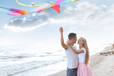 快乐的年轻夫妇在海上放飞风筝