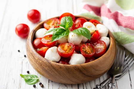 意大利 caprese 沙拉与樱桃西红柿, 芝士干酪和罗勒在白色木质背景。选择性聚焦