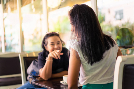 两个亚洲女人喜欢在咖啡馆里聊天喝咖啡。