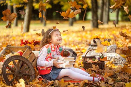 年轻的女孩，在秋天公园与书籍和小南瓜