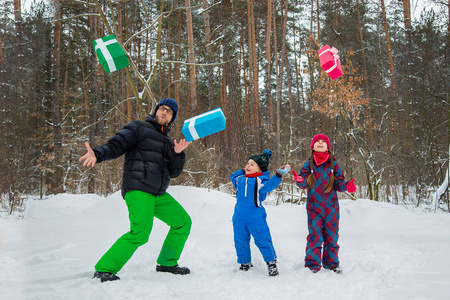 快乐的孩子们在冬日白雪覆盖的森林里配有礼品盒。圣诞节和新年的圣诞快乐