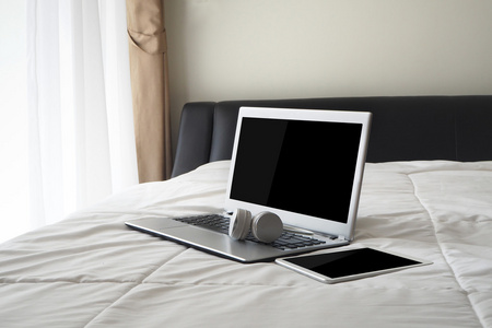 床上有空白屏幕笔记本和空白屏幕平板电脑。