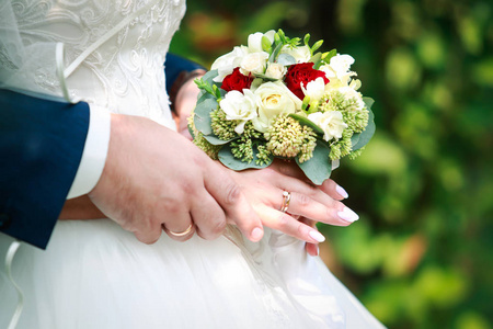 婚礼戒指上新娘和新郎的手指结婚花束