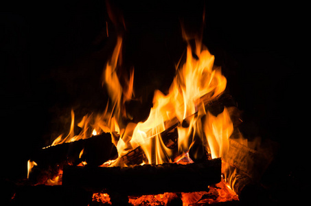 晚上烧木头。在山区的自然旅游营篝火。火焰 amd 火火花在黑暗的抽象背景。户外烹饪烧烤。地狱般的火元素。燃料电力和能源