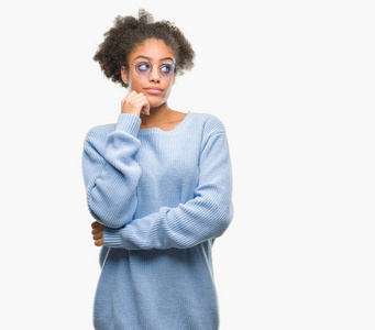 年轻的美国黑人妇女戴着眼镜在孤立的背景与手在下巴思考问题, 沉思的表达。微笑与周到的脸。怀疑概念
