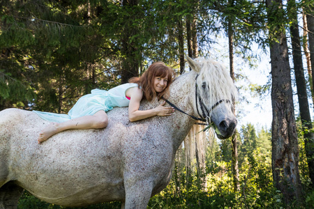 夏天阳光明媚的一天, 小女孩和白马在森林里