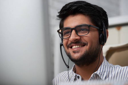 面对快乐的印度咨询服务经理说话的客户通过耳机