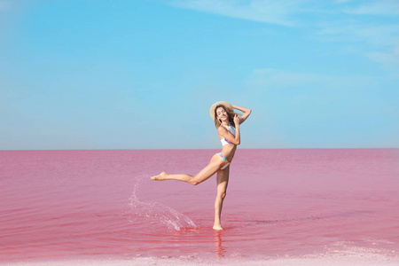 阳光明媚的一天, 穿着泳装的美女站在粉红湖边