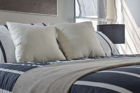 灰白色和条纹的枕头在床上，用在现代风格的卧室里的深蓝色条纹毯子