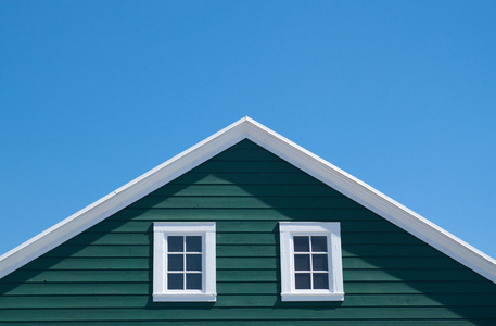 绿色的房子和白色的屋顶，与蔚蓝的天空中阳光灿烂的日子