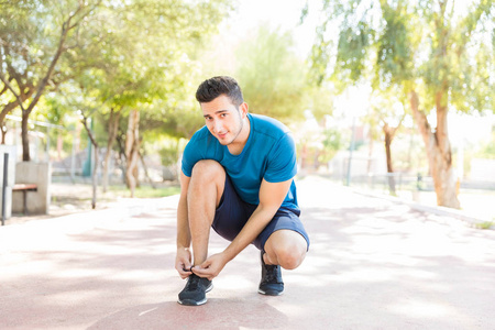 男运动员全长肖像在公园里跑步前系鞋带
