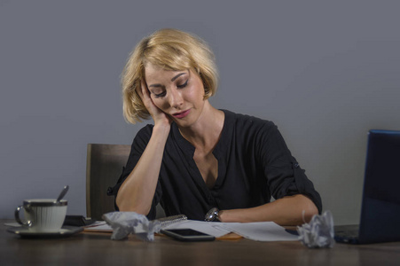 年轻美丽的压力和悲伤的金发女人工作与膝上型电脑感觉疲惫坐在办公桌上不堪重负的书面文件在业务压力概念中遭受抑郁症
