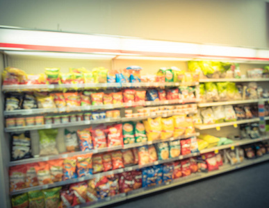 模糊图像的小吃和罐装薯条过道在简陋, 得克萨斯州, 美国。宽视角查看货架各种小吃, 弥散模糊背景散景光在超市。经营理念