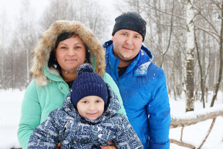 快乐的家庭 母亲, 父亲, 儿子 在降雪时摆姿势