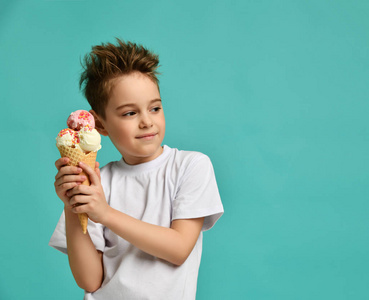 小男孩抱着草莓香草冰淇淋在华夫饼锥快乐的微笑尖叫着蓝色薄荷背景的咆哮