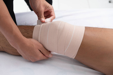 理疗师使用病人腿部的把手躺在医疗室的床上