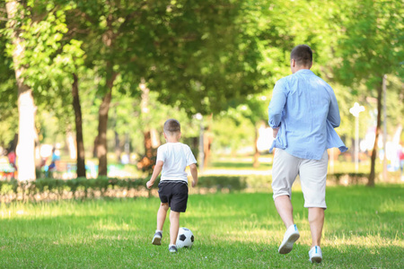 小男孩与他的爸爸在公园踢足球