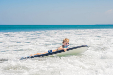 快乐的男孩游泳冲浪板上海浪在海洋