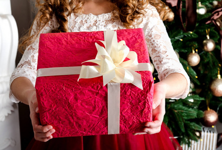 快乐的小女孩与礼品盒附近冷杉树在圣诞节时间特写