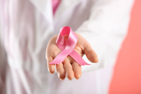 女医生持有粉红色丝带, 特写。乳癌概念