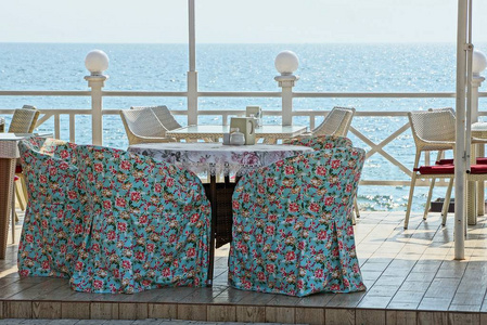 彩色扶手椅和一张桌子, 在夏日餐厅的户外露台上, 对着天空和大海
