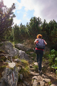 中年妇女与背包徒步旅行在山区的足迹白天