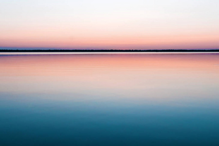 美丽的, 红色的黎明在湖上。太阳通过雾的光芒。湖面上的蓝天, 清晨来了, 森林映在水中