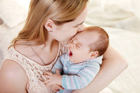 美丽的年轻母亲亲吻和拥抱她刚出生的男婴。母性观念。幸福家庭理念