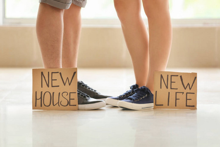 年轻夫妇的腿和纸板床单与文本新房, 新的生活。搬到新房的概念