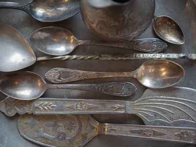 顶部拍摄的老式银器器皿餐具很多勺子在银托盘。平躺