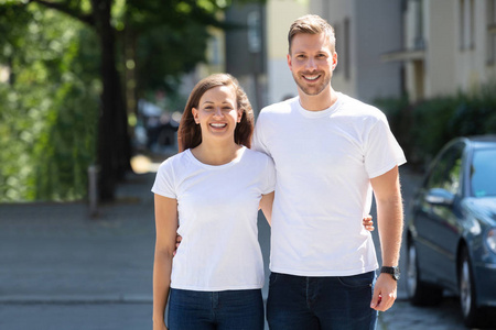 站在街上的一对微笑的年轻夫妇的肖像
