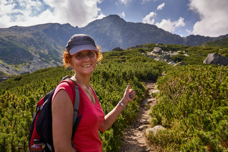 中年妇女与背包徒步旅行在山区的足迹白天