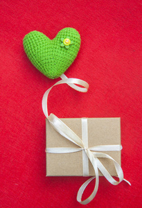 绿色针织心, 爱的象征, 像一个气球, 有一个红色的背景礼品盒