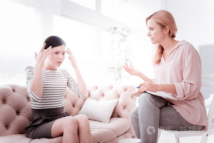 情绪化的女人解释一个问题和她的心理医生用心倾听