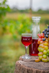 夏季草篮中的有机水果。新鲜的葡萄, 梨和苹果的性质。酒瓶和酒杯