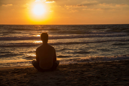 在夕阳的背景下, 一个人在美丽的海边的海滩上的剪影