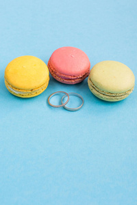 婚礼戒指上马卡龙或杏仁在绿松石背景上的看法。Macaron 从上面, 五颜六色的杏仁曲奇饼, 柔和的颜色
