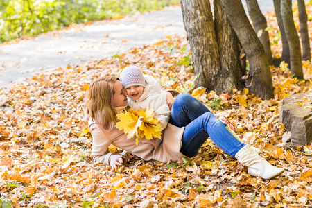 年轻的母亲和她蹒跚学步的女孩在秋季有乐趣