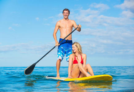 一对夫妇在夏威夷站着划桨冲浪