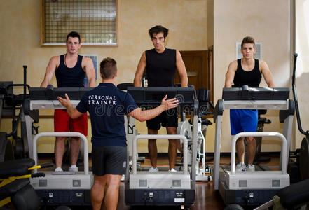 三个年轻人和私人教练在跑步机上锻炼