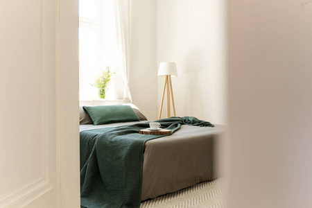 在一张打开的门上偷看, 穿着灰色和绿色的亚麻布, 枕头和毯子在一个生态友好的卧室内部。模糊了一张照片的一面。真实照片
