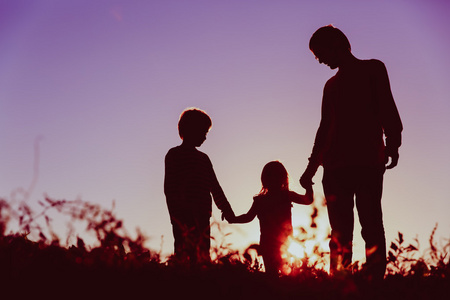 父亲与儿子和女儿走在日落时