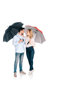 美丽的年轻夫妇抱着雨伞, 微笑着彼此孤立的白色