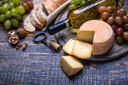 葡萄酒瓶 corkcrew 和一套产品奶酪 葡萄 坚果 橄榄 无花果上一块木板，在白色背景