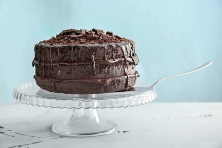 与美味的巧克力蛋糕站在桌子上反对颜色背景