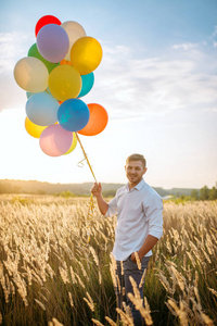 快乐的人带着一群气球走在麦田里