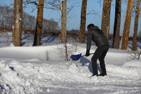 冬天, 男人用铲子把雪从路边移走。