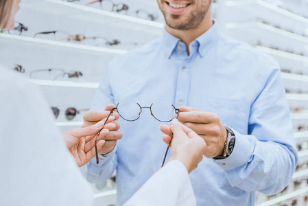 女性眼科在眼科店给年轻人戴眼镜的画面