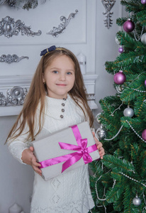 可爱微笑的小女孩，与附近的圣诞树礼品盒